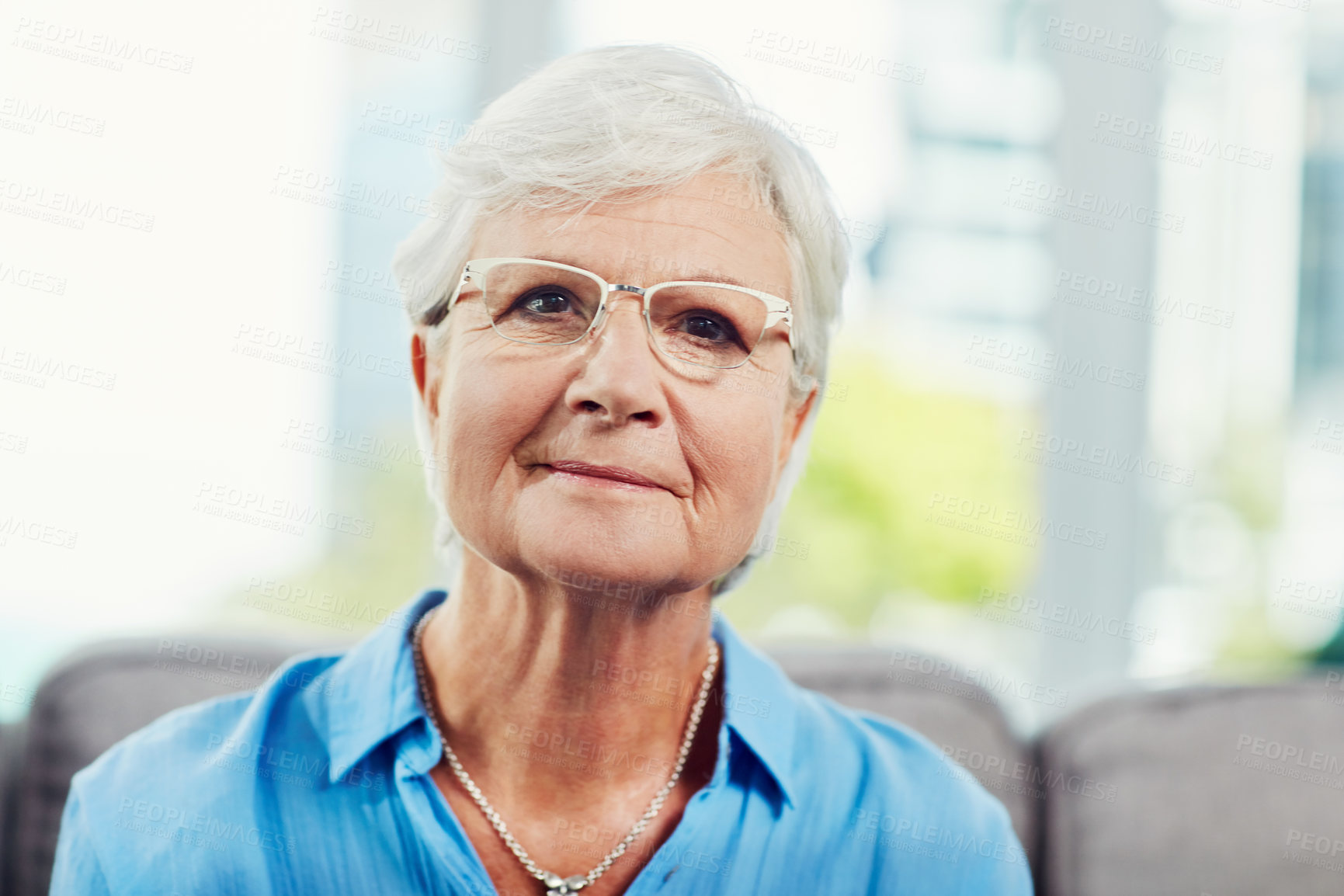 Buy stock photo Cropped portrait of a senior woman sitting on her sofa at home