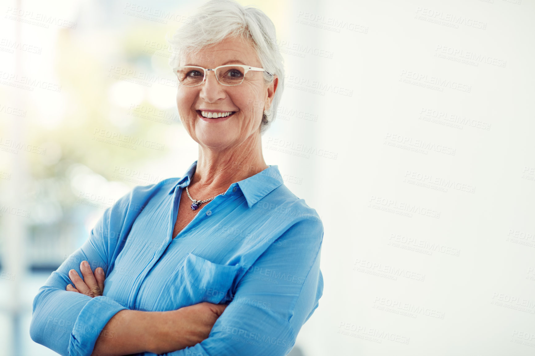 Buy stock photo Cropped portrait of a senior woman standing with her arms folded at home