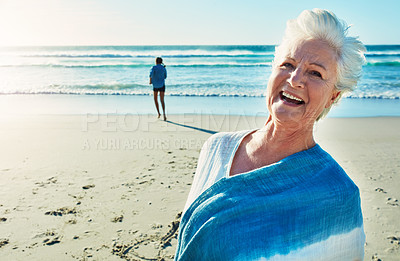 Buy stock photo Cropped portrait of a senior woman standing on the beach with her granddaughter in the background
