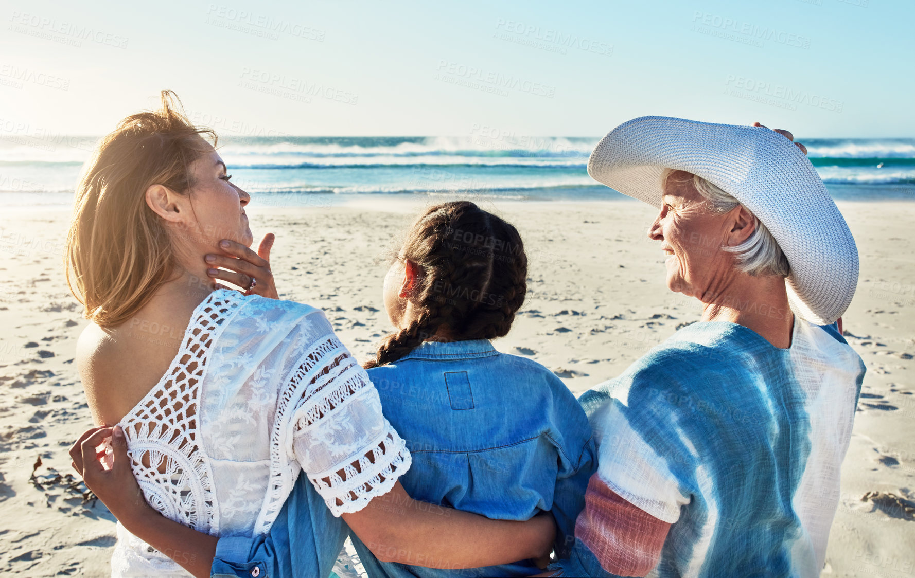 Buy stock photo Rearview shot of a senior woman spending the day at the beach with her daughter and granddaughter