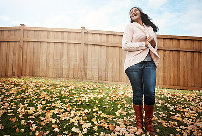 Buy stock photo Shot of a happy young woman in her backyard on an autumn’s day