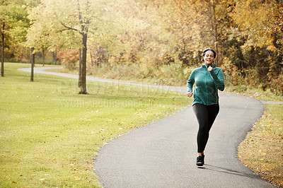 Buy stock photo Shot of an attractive young woman going for a run in nature