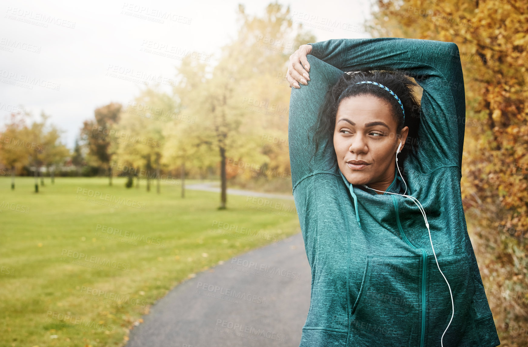 Buy stock photo Shot of an attractive young woman stretching while out for a run in nature