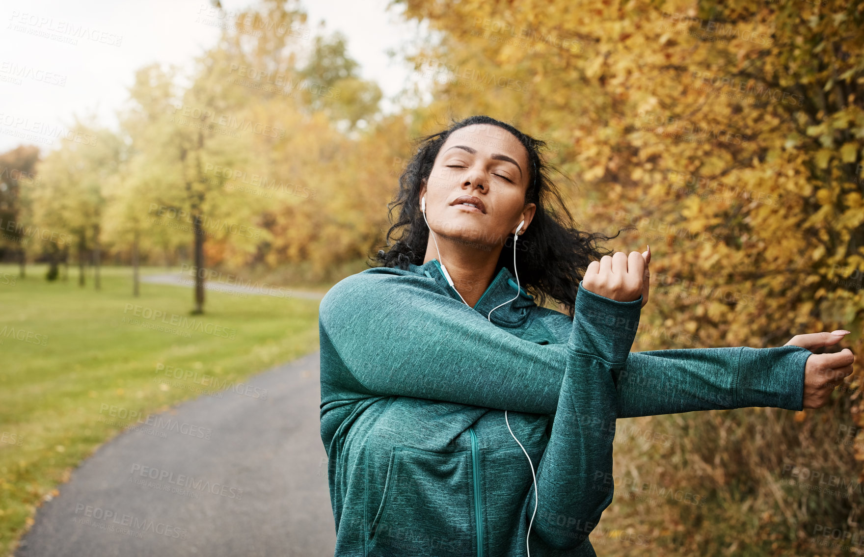 Buy stock photo Shot of an attractive young woman stretching while out for a run in nature