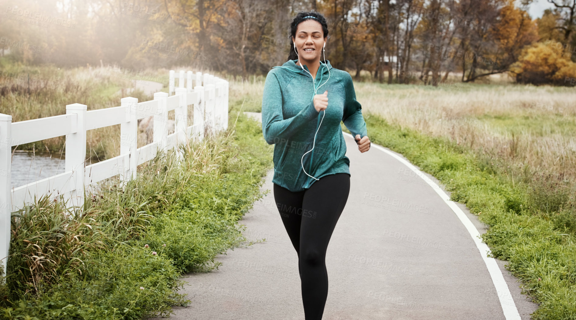 Buy stock photo Shot of an attractive young woman going for a run in nature