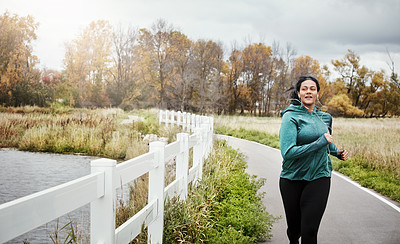 Buy stock photo Shot of an attractive young woman going for a run in nature