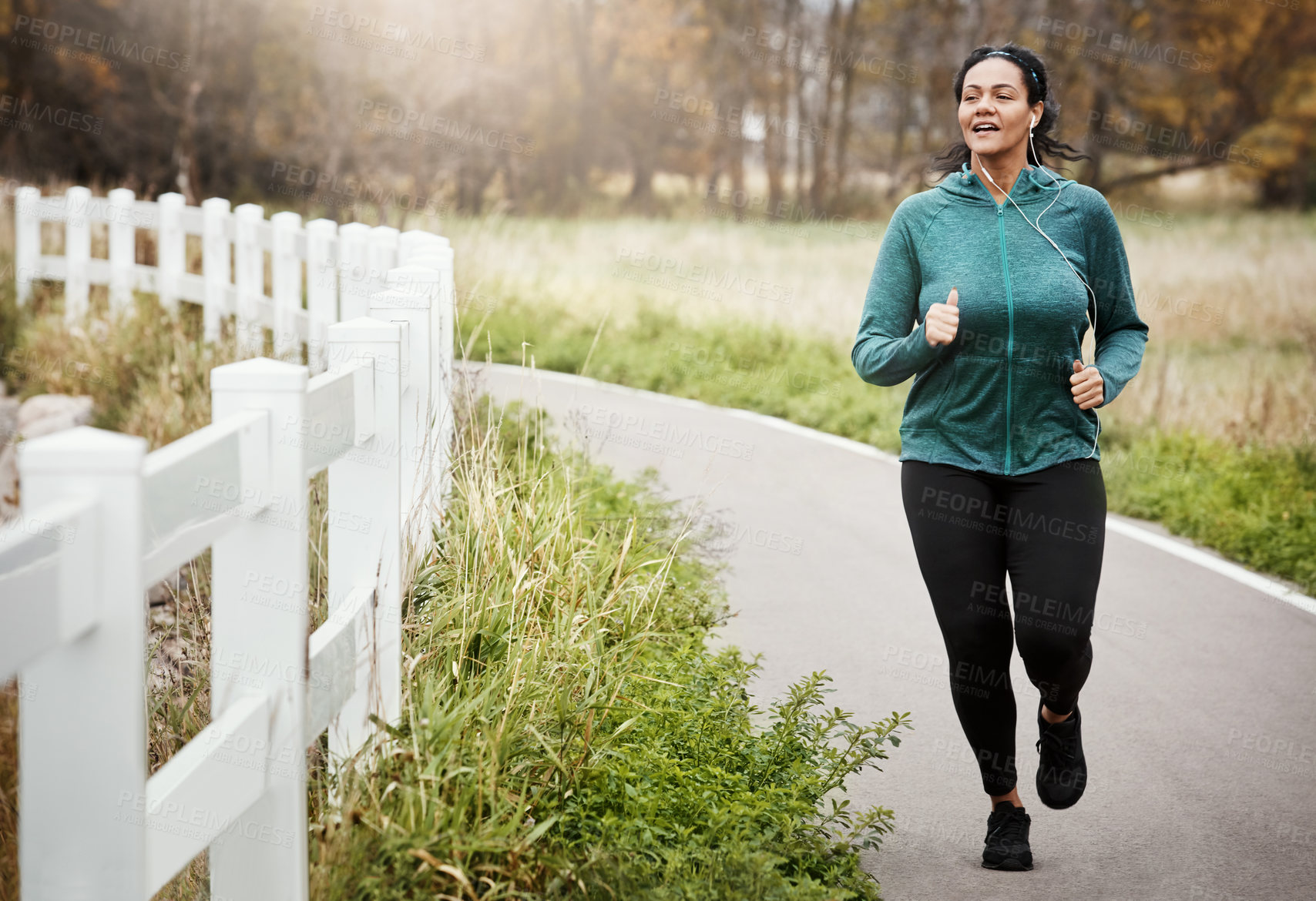 Buy stock photo Shot of an attractive young woman going for a run in nature