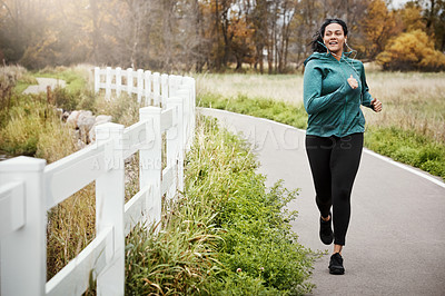 Buy stock photo Shot of an attractive young woman going for a run in nature