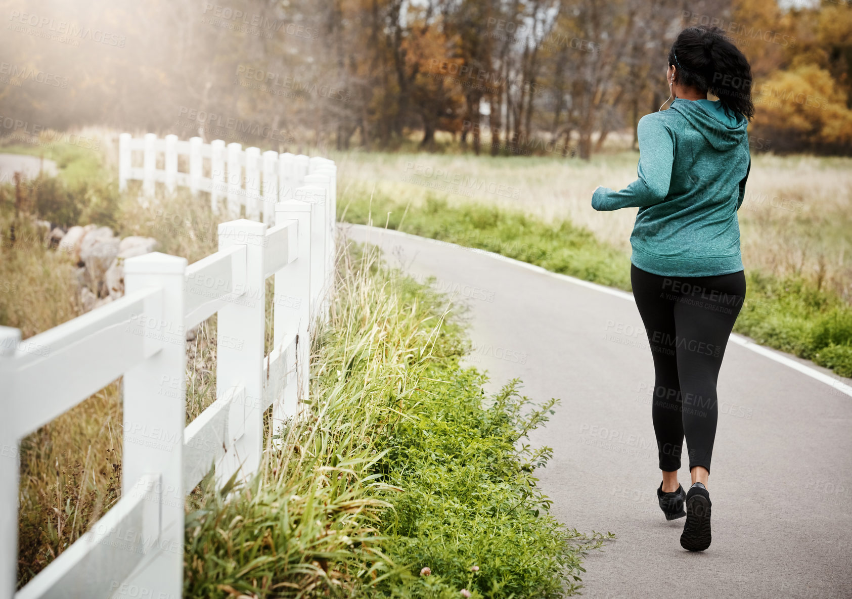 Buy stock photo Rearview shot of a young woman going for a run in nature