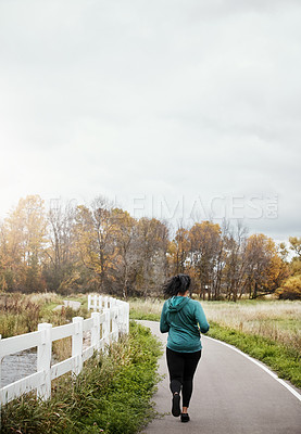 Buy stock photo Rearview shot of a young woman going for a run in nature