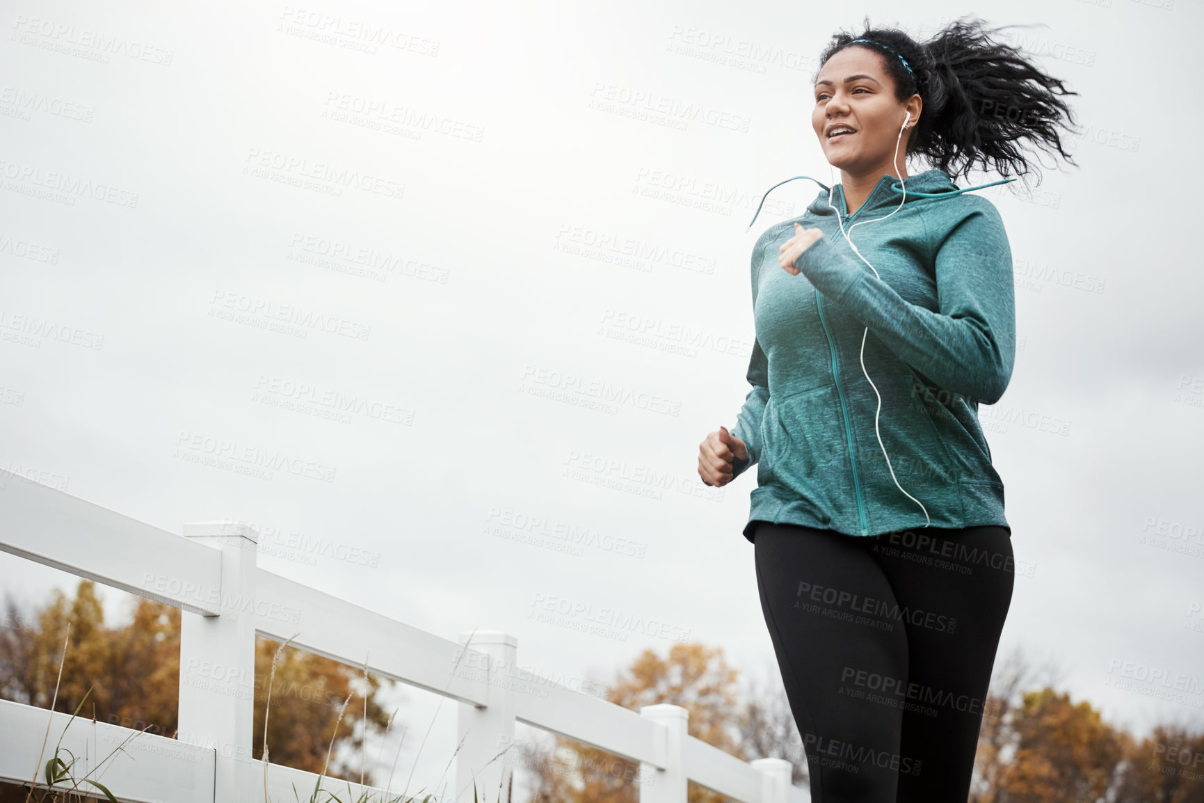 Buy stock photo Shot of an attractive young woman going for a run in nature