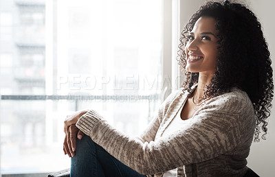 Buy stock photo Shot of a cheerful young woman relaxing while being seated on a chair at home during the day