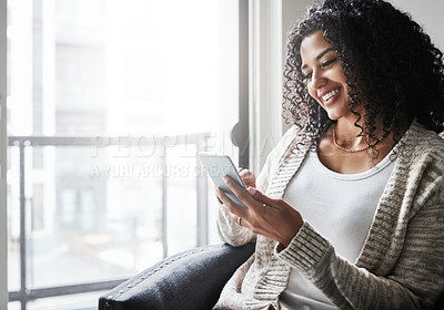 Buy stock photo Shot of a cheerful young woman relaxing while texting on her cellphone at home during the day