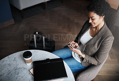 Buy stock photo Shot of a young businesswoman using a cellphone while waiting for her flight in an airport lounge