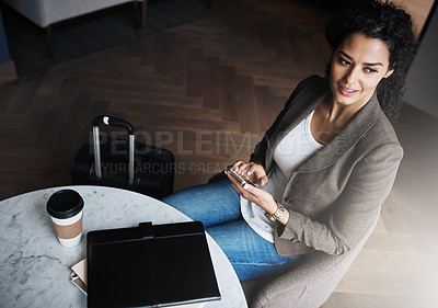 Buy stock photo Shot of a young businesswoman using a cellphone while waiting for her flight in an airport lounge