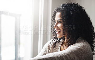 Buy stock photo Shot of a cheerful young woman relaxing while being seated on a chair at home during the day