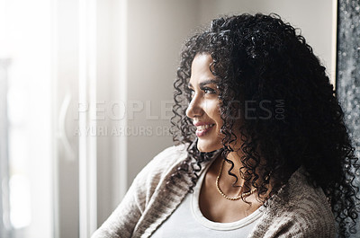 Buy stock photo Shot of a cheerful young woman relaxing while being seated on a chair at home during the day