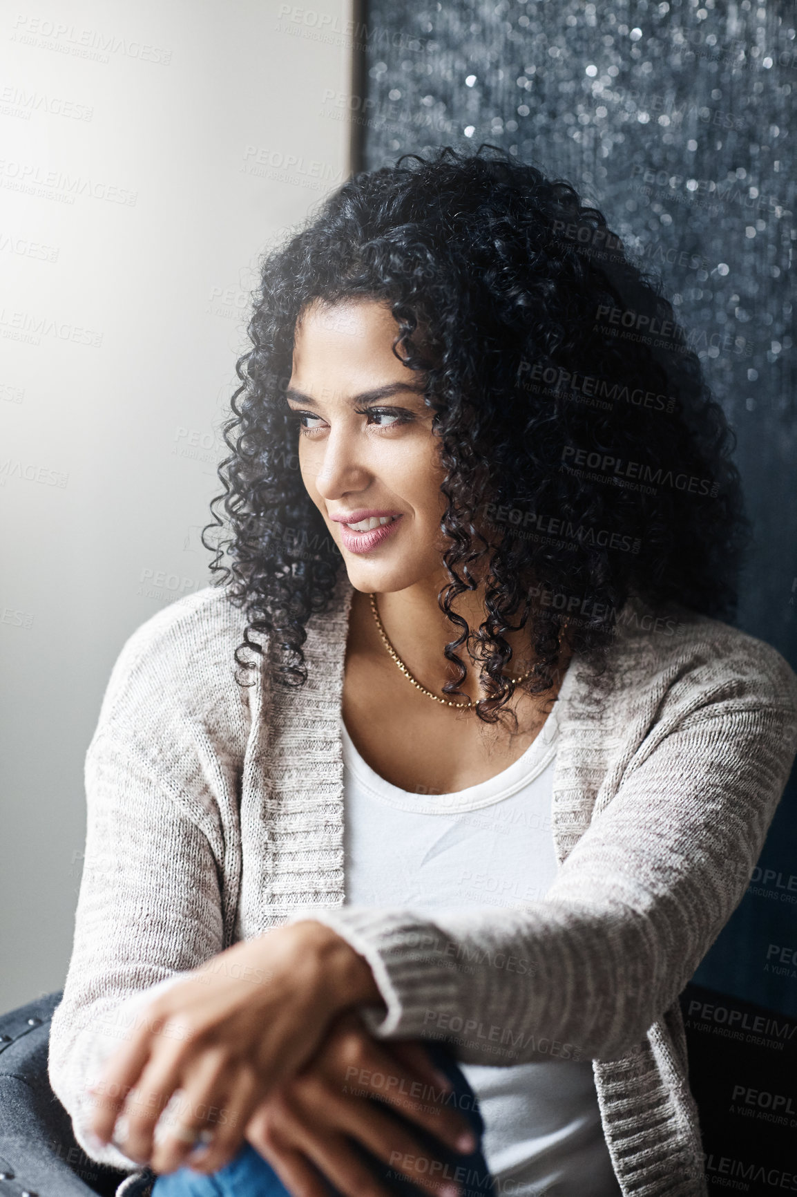 Buy stock photo Shot of a cheerful young woman relaxing while being seated on a chair at home during the day