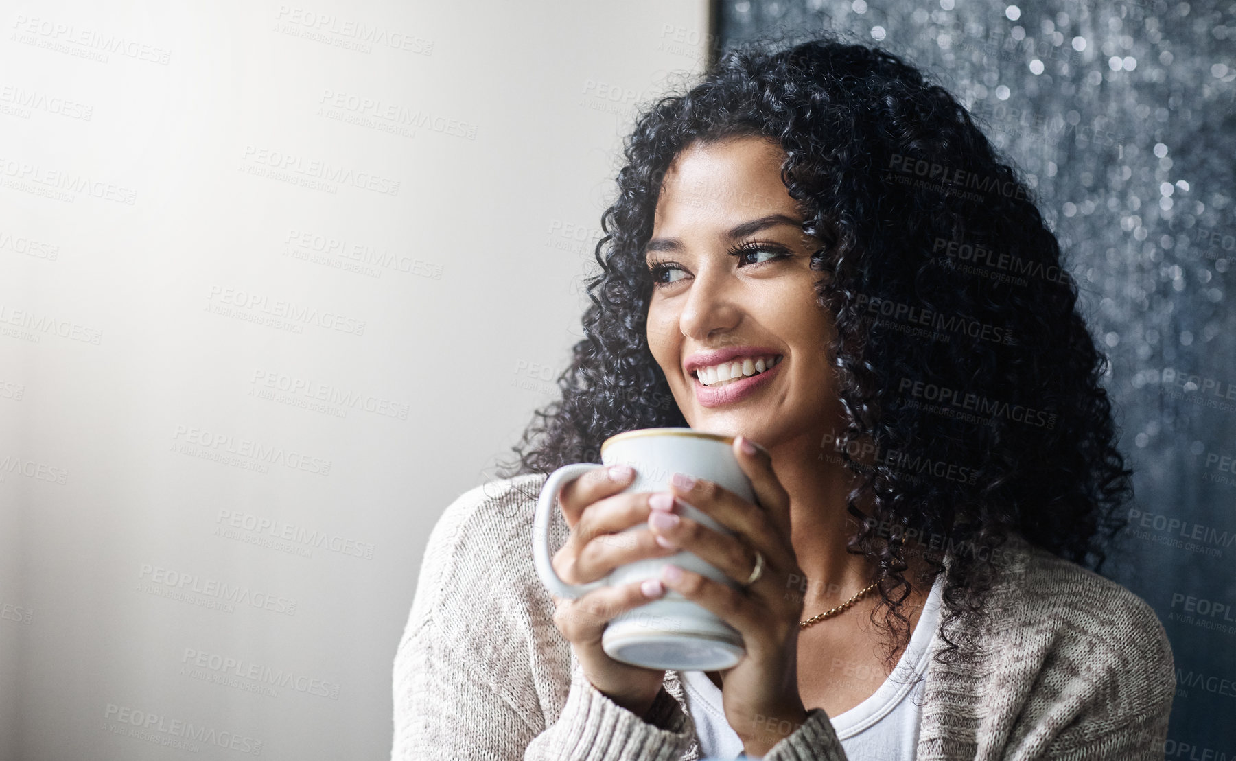 Buy stock photo Shot of a cheerful young woman enjoying a cup of coffee while being seated on a chair at home during the day