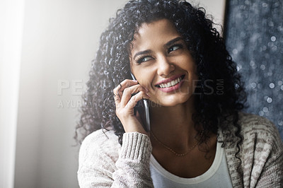 Buy stock photo Shot of a cheerful young woman relaxing while talking on her cellphone at home during the day
