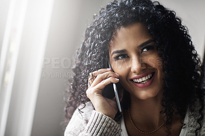 Buy stock photo Shot of a cheerful young woman relaxing while talking on her cellphone at home during the day