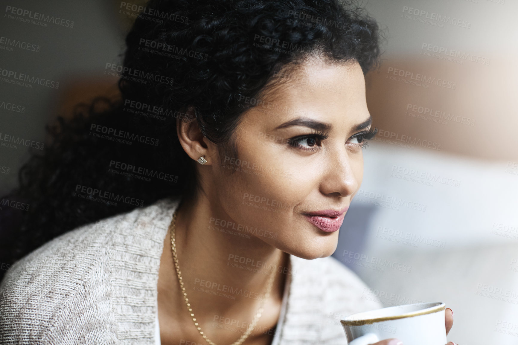 Buy stock photo Shot of an attractive young woman relaxing at home with a cup of coffee