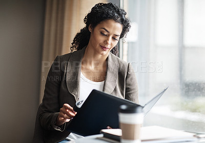 Buy stock photo Shot of a young businesswoman reading through a business folder in a cafe