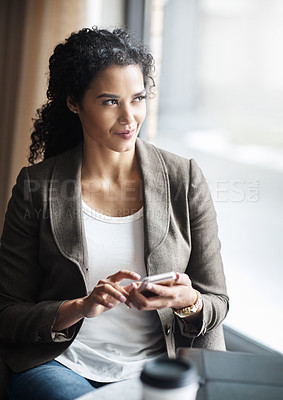 Buy stock photo Shot of a young businesswoman using a cellphone in a cafe