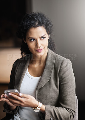 Buy stock photo Shot of a young businesswoman using a cellphone in an office