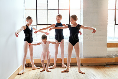 Buy stock photo Shot of a group of young ballerinas teaching a little girl ballet in a dance studio