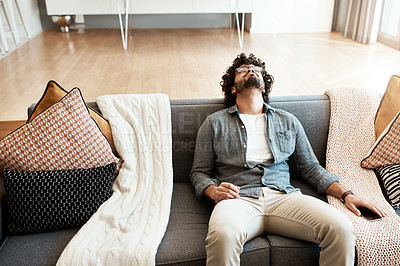 Buy stock photo Shot of a handsome young man relaxing on the couch at home