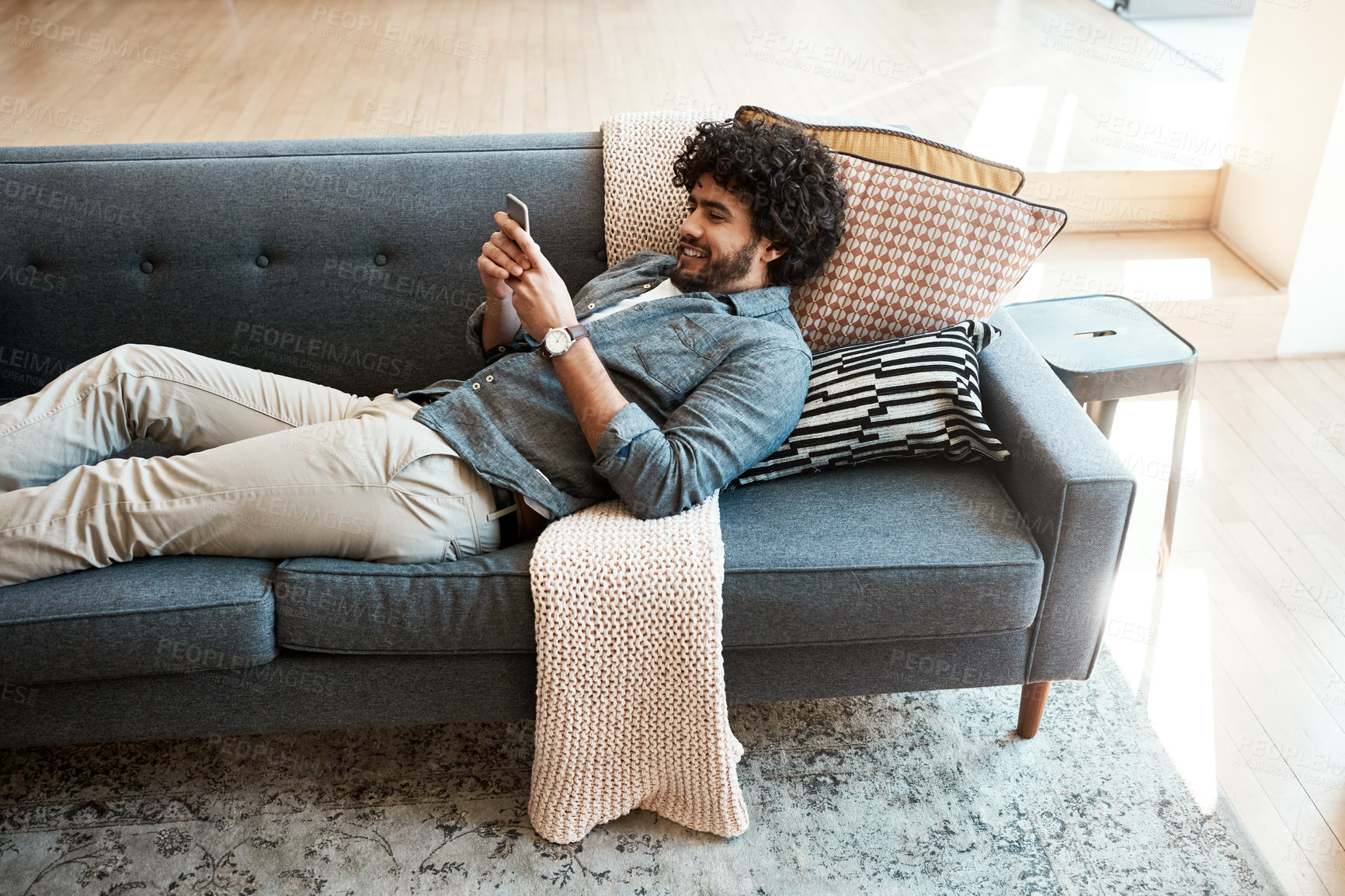 Buy stock photo Home, smile and man with phone on sofa for social network, communication and digital connection. Calm, relax and person with tech in living room for sports results, information or reading online news