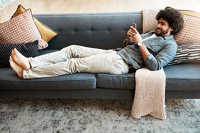 Buy stock photo Smile, relax and man with phone on sofa for social network, information and digital connection. Calm, home and person with tech in living room for sports results, communication or reading online news