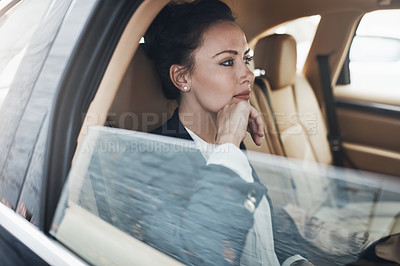 Buy stock photo Shot of a confident young businesswoman seated in a car as a passenger on her way to work during the day