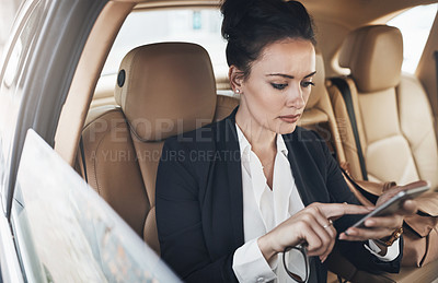Buy stock photo Shot of a confident young businesswoman seated in a car as a passenger while texting on her phone on her way to work