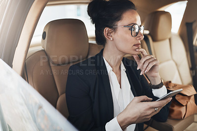 Buy stock photo Shot of a confident young businesswoman seated in a car as a passenger while texting on her phone on her way to work