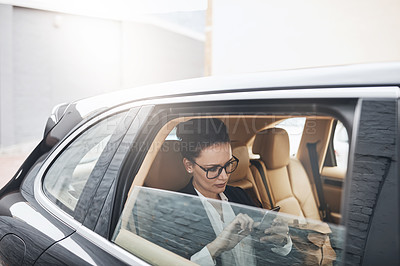 Buy stock photo Shot of a confident young businesswoman seated in a car as a passenger while texting on her phone on her way to work