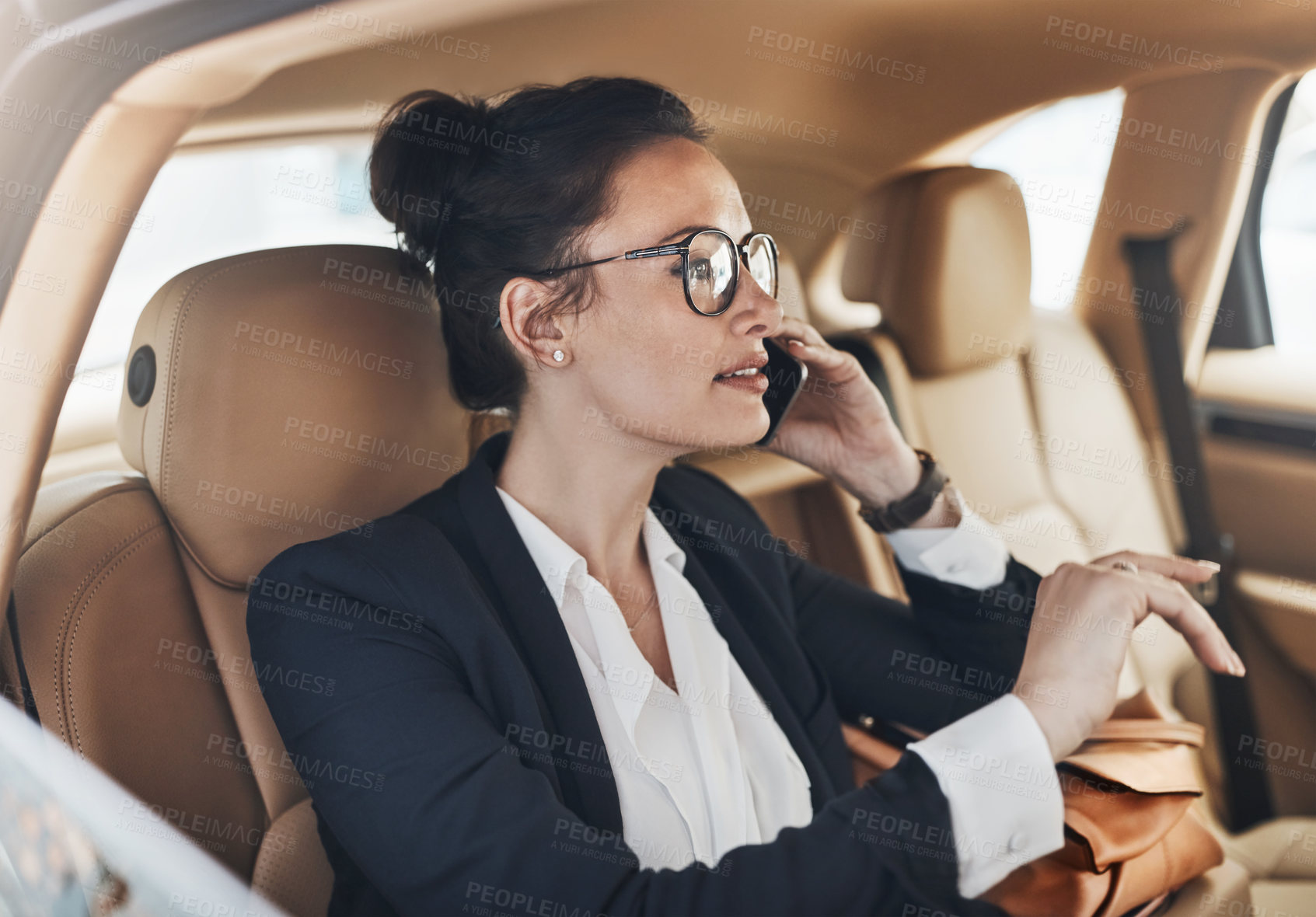 Buy stock photo Shot of a confident young business woman seated in a car as a passenger and talking on her cellphone while  going to work