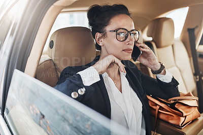 Buy stock photo Shot of a confident young business woman seated in a car as a passenger and talking on her cellphone while  going to work