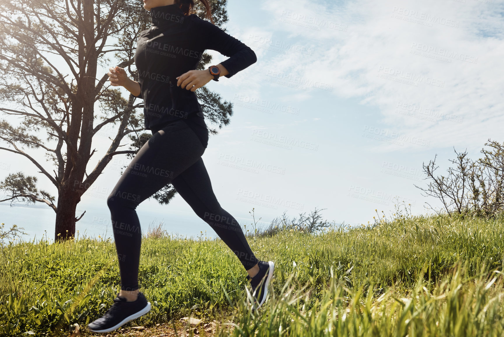 Buy stock photo Shot of an unrecognizable young woman going for a jog on her own with a view of the ocean in the background