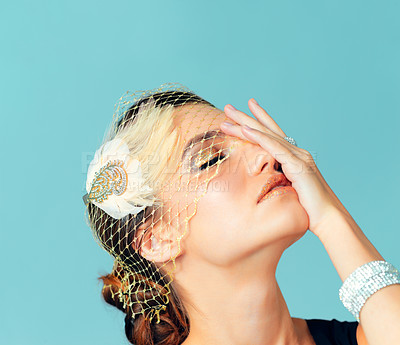 Buy stock photo Studio shot of an elegantly dressed young woman posing against a blue background