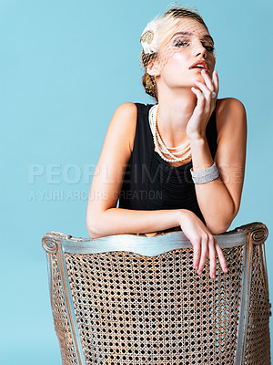 Buy stock photo Studio shot of an elegantly dressed young woman posing against a blue background