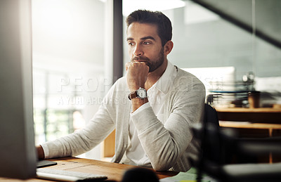 Buy stock photo Shot of a handsome young businessman working late on a computer in an office