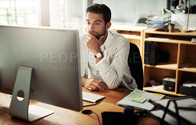 Buy stock photo Shot of a handsome young businessman working late on a computer in an office