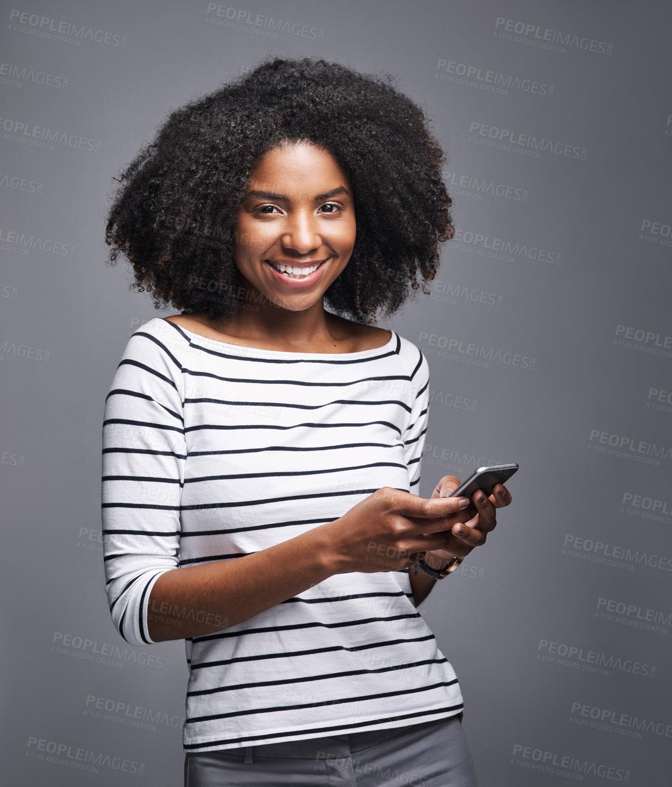 Buy stock photo Studio portrait of a young woman using a mobile phone against a gray background