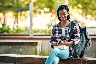 Buy stock photo Shot of a young female student using a cellphone outside on campus