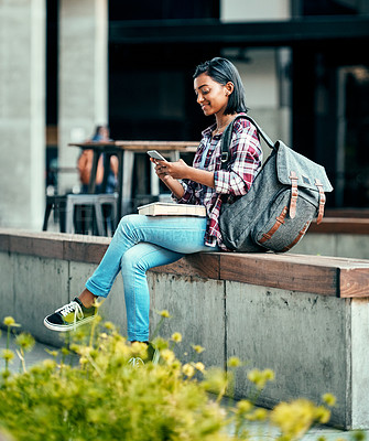 Buy stock photo Shot of a young female student using a cellphone outside on campus