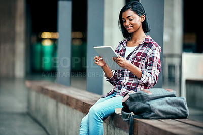 Buy stock photo Shot of a young female student using a tablet outside on campus