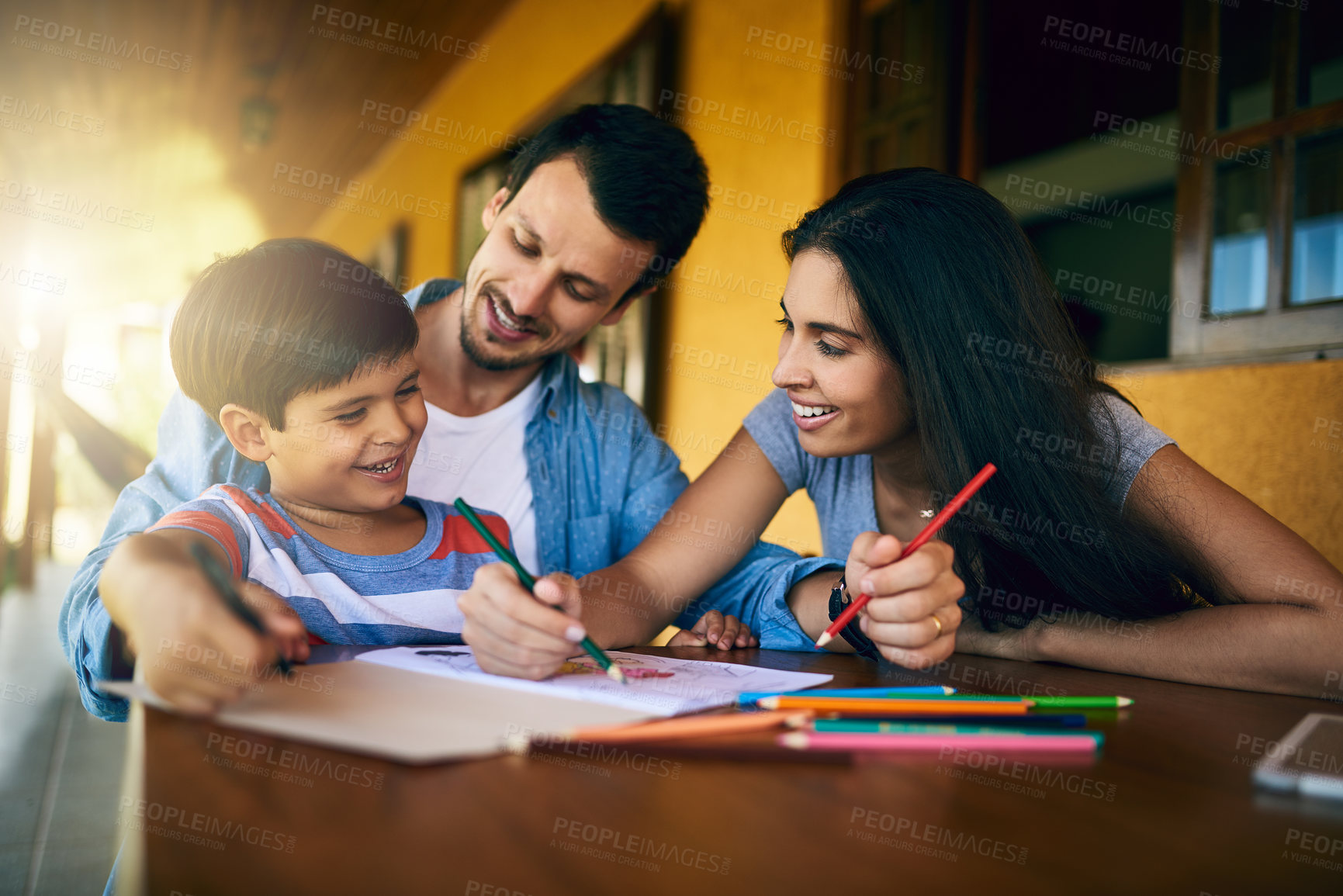 Buy stock photo Cropped shot of young affectionate parents colouring in pictures with their adorable son at home