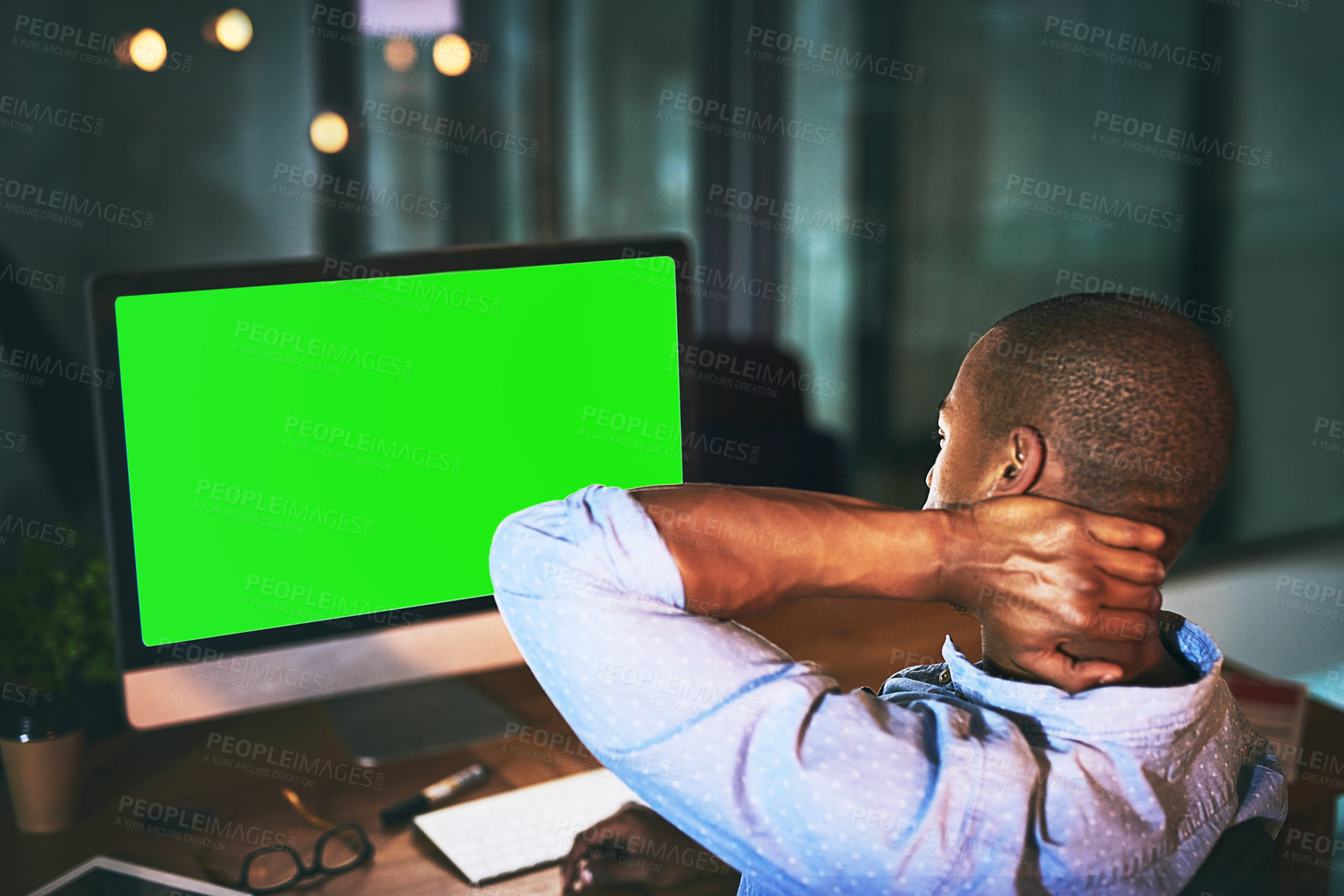 Buy stock photo Shot of a young businessman experiencing tension while using a computer with a green screen late at work